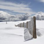 Snowy Vault - brown wooden fence on snow field under gray clouds