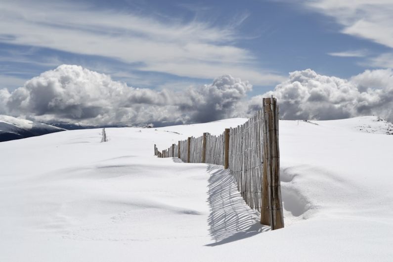 Snowy Vault - brown wooden fence on snow field under gray clouds