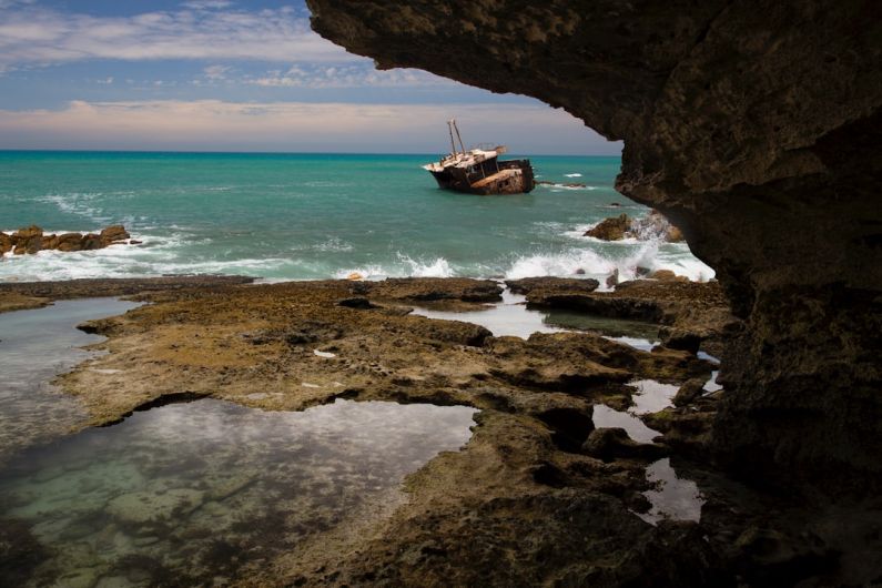 Wave Cave - brown and white fishing vessel near rock formation